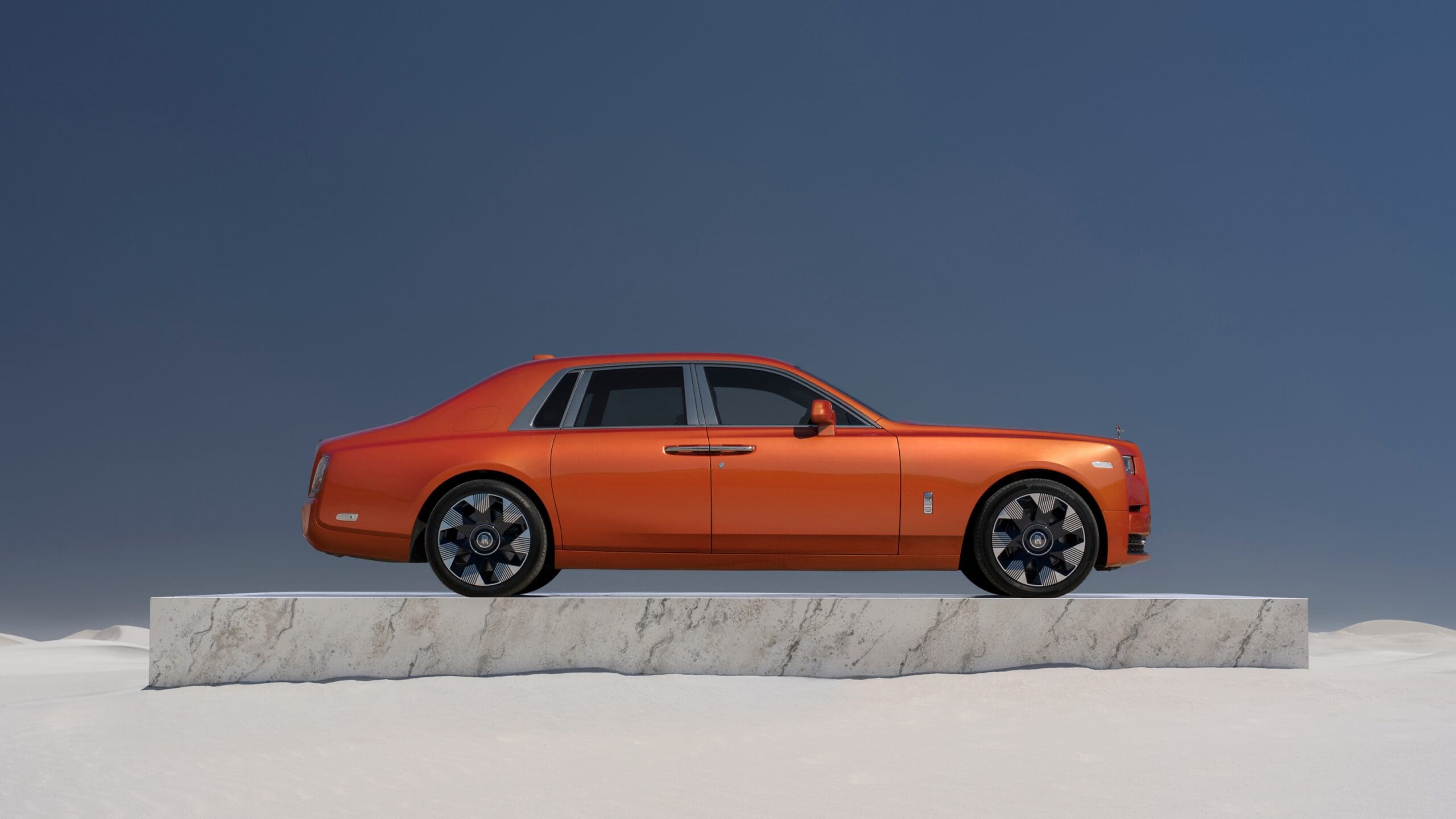 Side profile of an orange Phantom on a marble slab in the middle of the desert